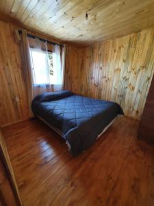 een slaapkamer met een bed in een houten hut bij Cabañas Llepu in Linares