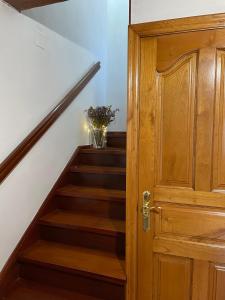 una escalera con una puerta de madera y un jarrón de flores en El escondite de Torazo, en Torazo