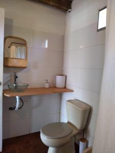a bathroom with a toilet and a sink and a mirror at La casita de Valizas in Barra de Valizas