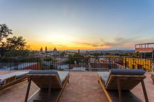 a rooftop patio with two beds and a sunset at Casa Almira 5BR Luxury Home with Pool, Hot Tub & Rooftop in San Miguel de Allende