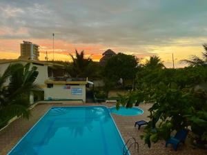 a swimming pool in front of a house with a sunset at Hostal La Tolita in Atacames