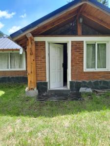 una casa con puerta blanca y porche en Entre Maitenes en Lago Puelo