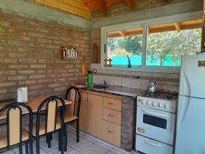 cocina con nevera blanca y mesa con sillas en Entre Maitenes en Lago Puelo
