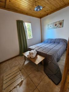 Un dormitorio con una cama y una mesa. en Cabañas Entre Cumbres en Moquehue