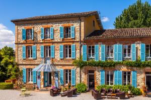 a large brick building with blue shutters on it at La Verrerie in Gaillac