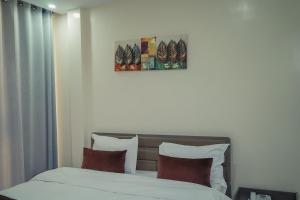 a bedroom with a bed with white sheets and red pillows at Urban Hotel Nouakchott in Nouakchott