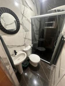 een badkamer met een toilet, een wastafel en een spiegel bij Residência Grafite in Saquarema +7 foto's