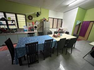 eine Küche mit einem Tisch und Stühlen sowie eine Küche mit einem Kühlschrank in der Unterkunft Homestay Hjh Rokiah, F.Tementi 