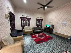 sala de estar con sofá y TV en Homestay Hjh Rokiah, F.Tementi, 