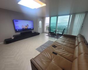 een woonkamer met een bank en een flatscreen-tv bij Gyeongdo CC and Ocean view in Yeosu