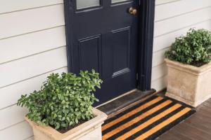 a black door with two potted plants on a house at Benambra Cottage - Pet Friendly in Queenscliff