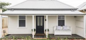 a white house with a porch with two chairs at Benambra Cottage c1860 - PET FRIENDLY in Queenscliff