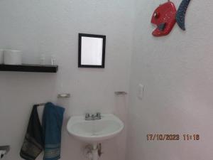 a bathroom with a sink and a red mask on the wall at Brisa de Mar in El Ojito +7 photos