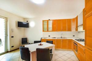 eine Küche mit Holzschränken sowie einem Tisch und Stühlen in der Unterkunft La Terrazza moderno con terrazza in Caprino Veronese