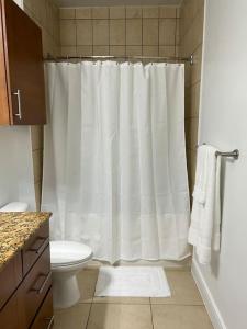 a bathroom with a white shower curtain and a toilet at The Bentler #2 in Houston
