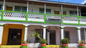 a building with white and green trim and potted plants at Posada Nativa Trinsan Centro in San Andrés