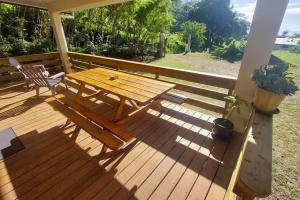 a wooden deck with a picnic table and a chair at Petite Maison Premium vue mer in Moorea