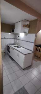 cocina blanca con fregadero y fogones en Casa Ana2, a 20 min del aeropuerto de ezeiza en Luis Guillón