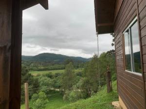 uma vista para um campo a partir de uma janela de uma casa em Pousada Vale do Tigre em Rio Rufino