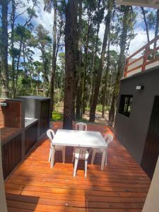 een witte tafel en stoelen op een houten terras bij BOSQUE LIBERTAD Casa PB in Mar Azul