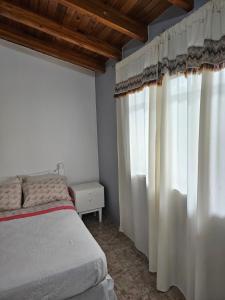 - une chambre avec des rideaux blancs et un lit dans l'établissement Alojamiento Ado, à Luján de Cuyo