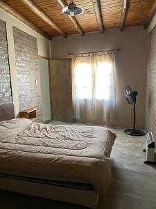 a bedroom with a bed with a window and a fan at EL TOPON cabañas in Albardón