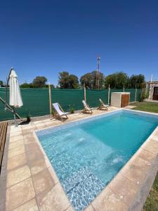 a swimming pool with two chairs and an umbrella at EL TOPON cabañas in Albardón