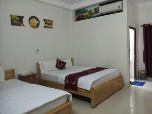 a bedroom with two beds and a tv on the wall at hằng hiên hotel in Lục Ngạn