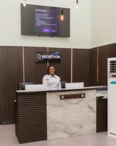 a woman sitting at a reception desk in an office at ED&DRE Luxuria Hotel in Ibadan