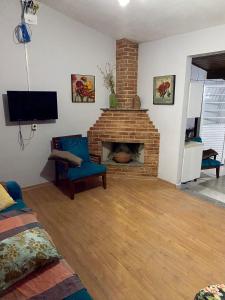 uma sala de estar com uma lareira de tijolos e uma televisão em Chácara Serra Negra em Serra Negra