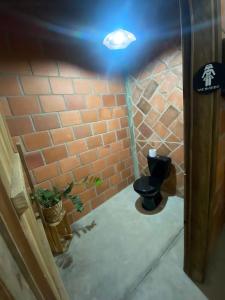 uma casa de banho com um WC e uma parede de tijolos em Chácara Serra Negra em Serra Negra