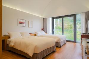 two beds in a hotel room with a window at Healing Stay KOSMOS in Ullŭng