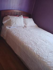an unmade bed with white sheets and pillows at cabañas jessy in Valdivia