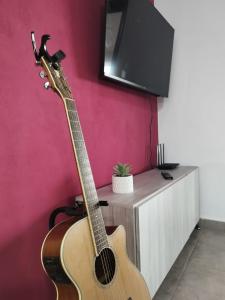 a guitar leaning against a wall next to a tv at Estancia Borke - Carlos Paz in Estancia Vieja