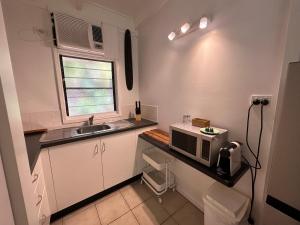 uma pequena cozinha com um lavatório e um micro-ondas em Magnetic Island Resort Studio em Nelly Bay