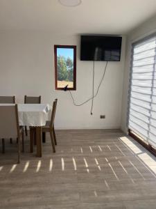 a dining room with a table and a television on a wall at Cabaña Viaducto Vista al Mar, Curanipe in Pelluhue