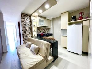 eine Küche mit einem Sofa und einem weißen Kühlschrank in der Unterkunft Apê 4: Pé na Areia Maragogi - O Caribe Brasileiro in Maragogi