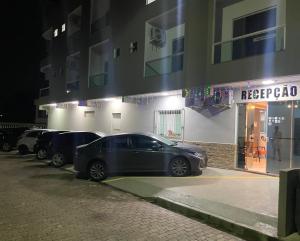 une voiture garée devant un bâtiment la nuit dans l'établissement Pousada Ventura, à Anchieta