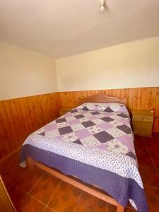 1 dormitorio con 1 cama con edredón morado y blanco en Casa cerca de la playa, en Los Vilos