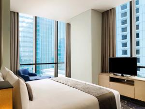 a hotel room with a large bed and a television at Mangkuluhur Residences by Lorin in Jakarta