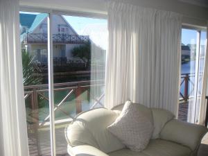 a white couch sitting in front of a large window at WatersideLiving MS11 in Jeffreys Bay