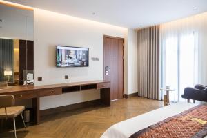 a hotel room with a desk and a tv on the wall at Hotel Trí Lê PREMIER in Cao Lãnh