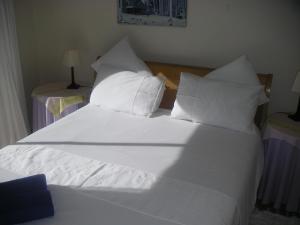una cama blanca con sábanas y almohadas blancas en WatersideLiving MS11, en Jeffreys Bay