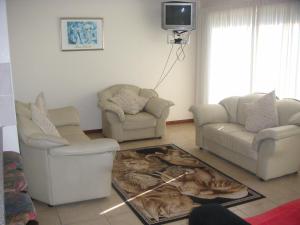 a living room with two chairs and a tv at WatersideLiving MS11 in Jeffreys Bay