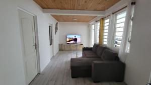 a living room with a couch and a flat screen tv at Maison d'Hanaya in Le Marin