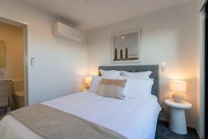 1 dormitorio con 1 cama blanca grande y 2 lámparas en Harbour Haven - A Sunset Oasis! en Tauranga