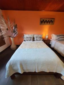 een slaapkamer met een groot bed met een oranje muur bij Hospedaje rural - Finca la Aurora - Caqueza in Cáqueza