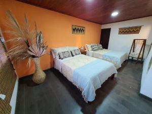 a bedroom with two beds and a vase with a plant at Hospedaje rural - Finca la Aurora - Caqueza in Cáqueza