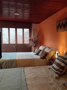 twee bedden in een kamer met oranje muren en ramen bij Hospedaje rural - Finca la Aurora - Caqueza in Cáqueza