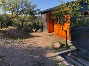 a small house with a wooden door and a tree at Molle Alojamiento Serrano in Villa Icho Cruz